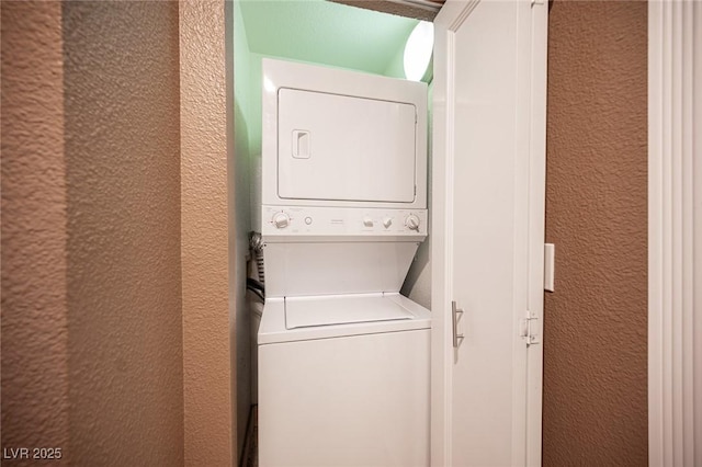 laundry room with stacked washer / dryer, laundry area, and a textured wall