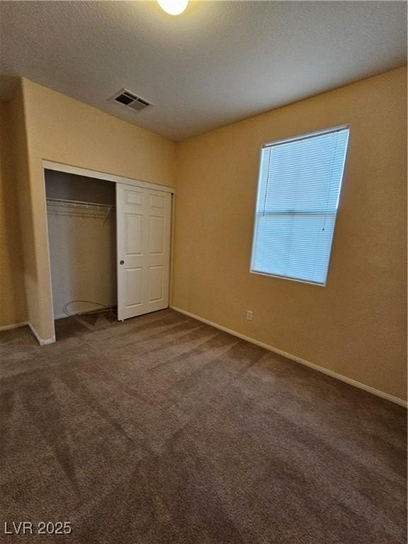 unfurnished bedroom with a closet, visible vents, carpet flooring, and baseboards