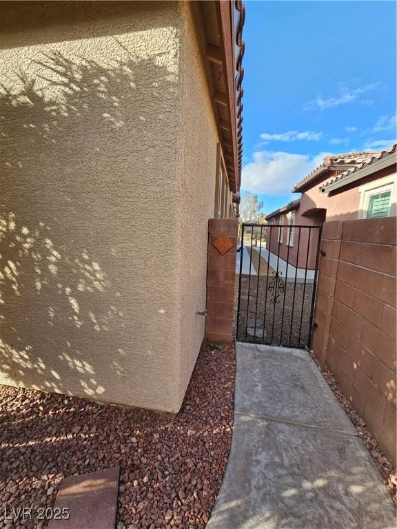 view of property exterior with stucco siding, fence, and a gate