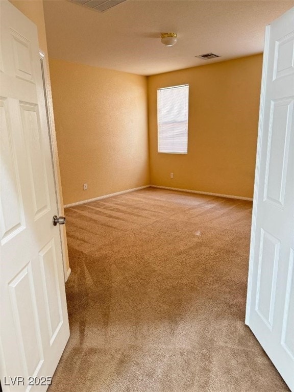 empty room featuring light carpet, visible vents, and baseboards