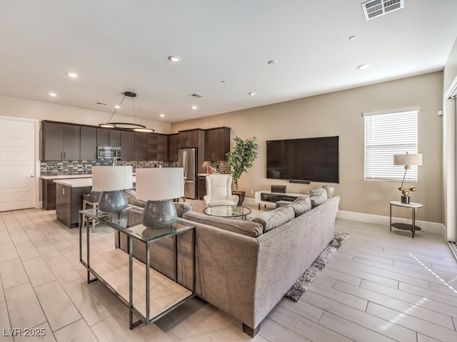 living area with recessed lighting, visible vents, light wood finished floors, and baseboards