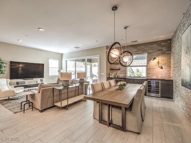 dining area with wine cooler, a healthy amount of sunlight, visible vents, and light wood-style flooring