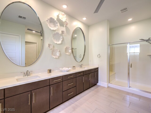 full bathroom with double vanity, visible vents, a shower stall, and a sink