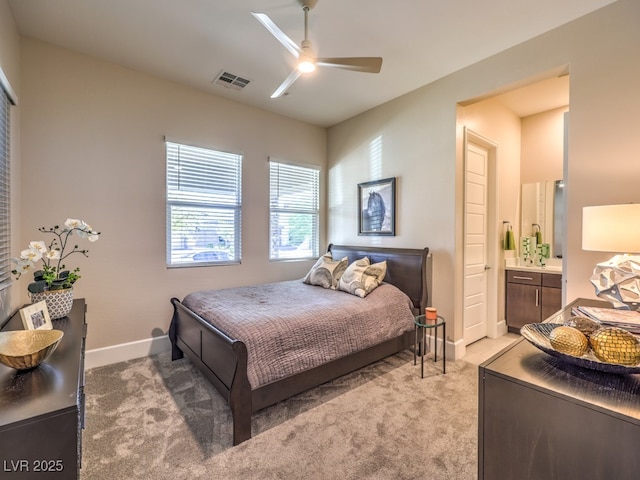 bedroom featuring visible vents, baseboards, ceiling fan, light colored carpet, and connected bathroom