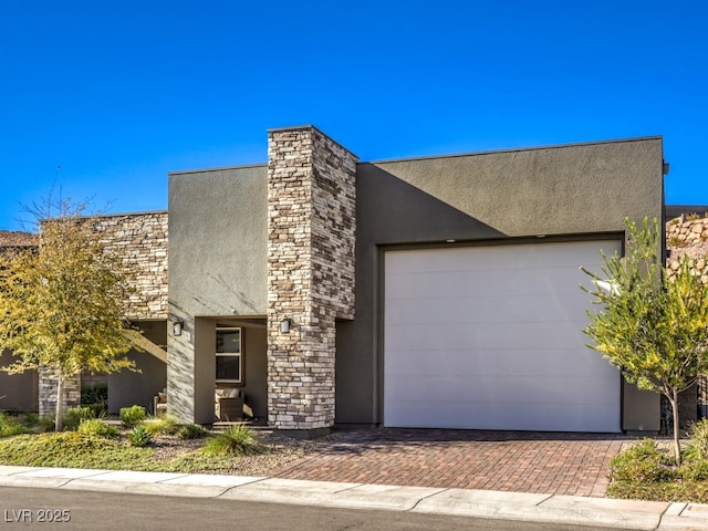 view of front of house featuring stone siding, stucco siding, decorative driveway, and an attached garage