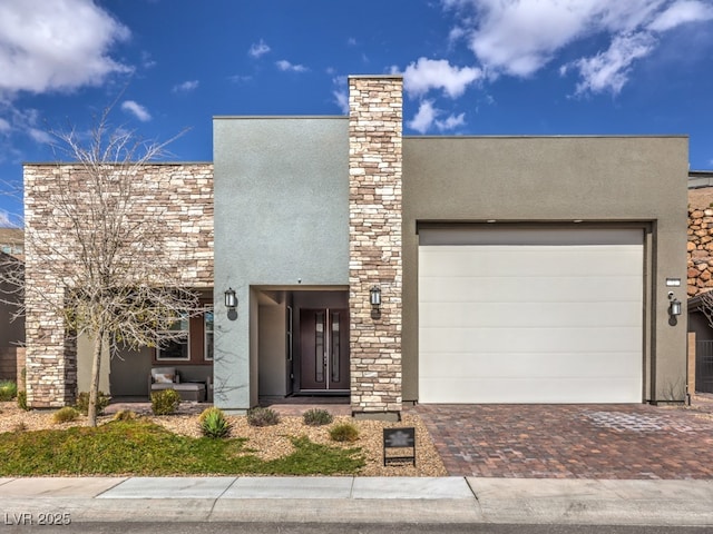 view of front of house with decorative driveway, a garage, and stucco siding