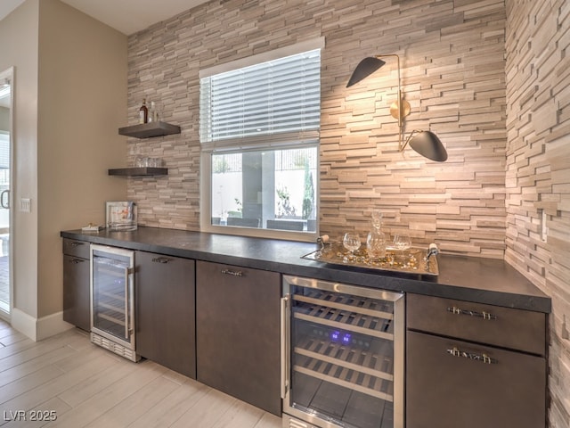 bar featuring indoor wet bar, beverage cooler, baseboards, and wood finish floors