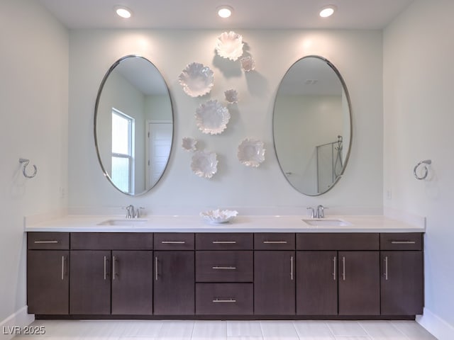 bathroom with double vanity, recessed lighting, baseboards, and a sink