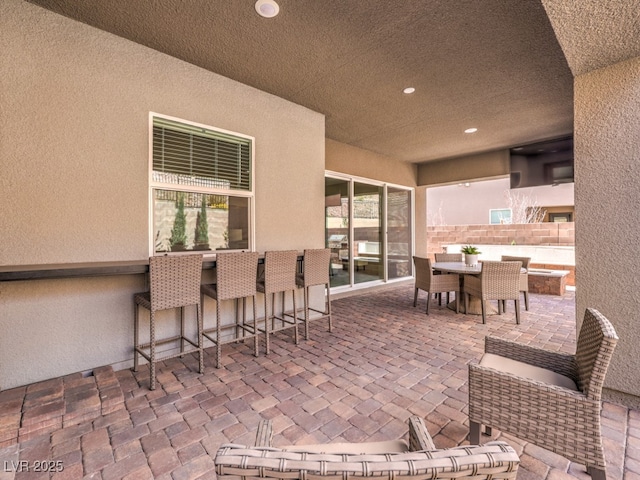 view of patio with outdoor dining space, fence, and outdoor dry bar