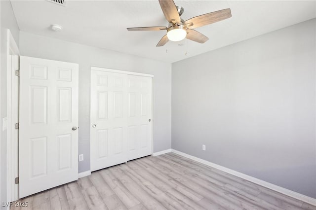 unfurnished bedroom with a closet, baseboards, ceiling fan, and light wood finished floors