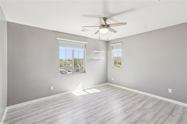 empty room with visible vents, a ceiling fan, baseboards, and wood finished floors