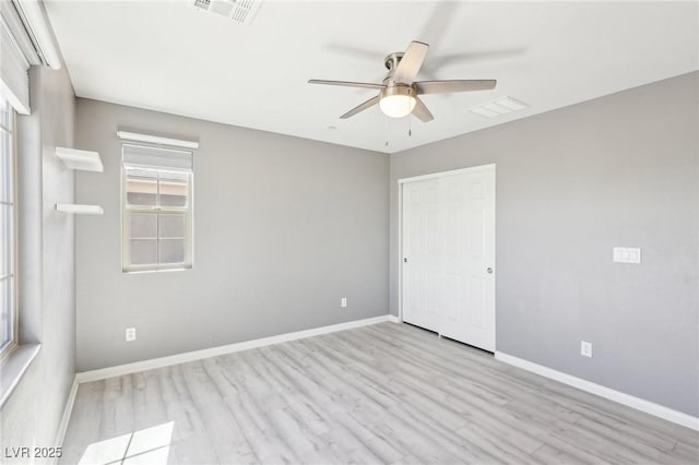 spare room with a ceiling fan, wood finished floors, baseboards, and visible vents