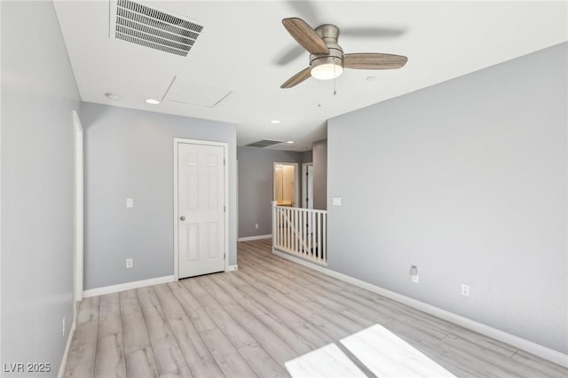 unfurnished room featuring attic access, wood finished floors, baseboards, and visible vents