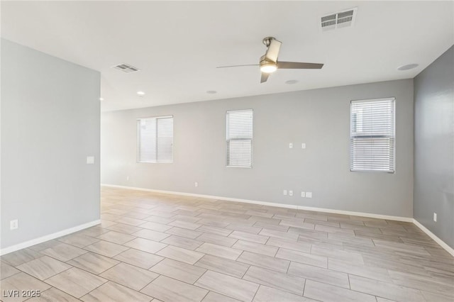 unfurnished room with visible vents, a ceiling fan, and baseboards