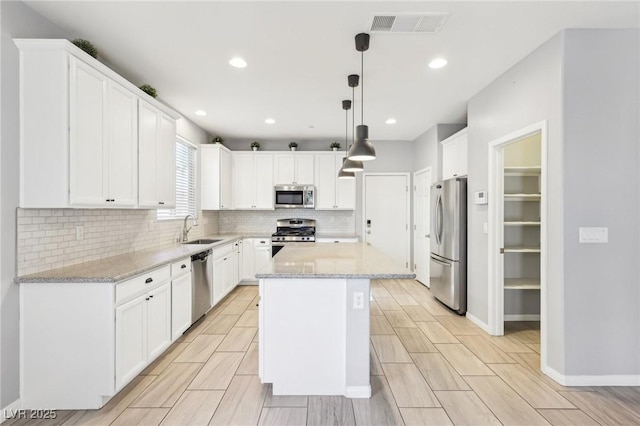 kitchen with tasteful backsplash, visible vents, a kitchen island, appliances with stainless steel finishes, and a sink