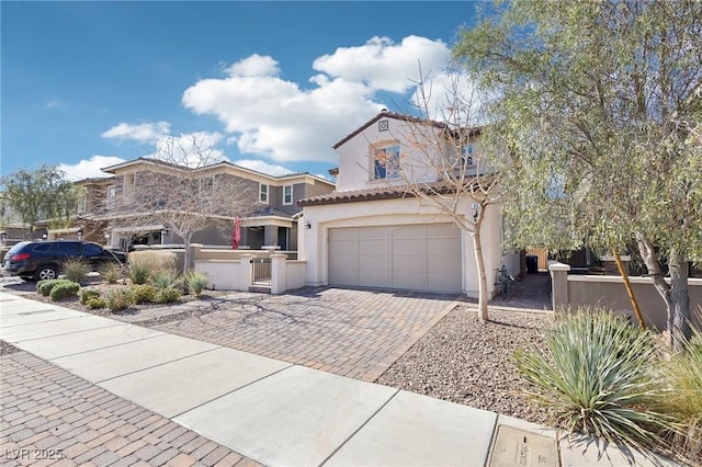 mediterranean / spanish home featuring decorative driveway, a garage, and stucco siding