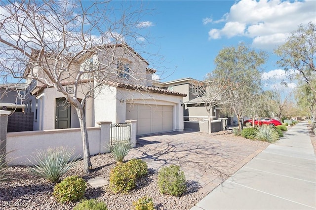 mediterranean / spanish home with an attached garage, driveway, a fenced front yard, and stucco siding