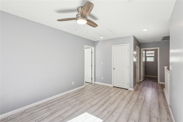 unfurnished bedroom with baseboards, visible vents, attic access, ceiling fan, and light wood-style floors