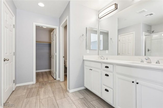 bathroom featuring double vanity, a stall shower, visible vents, and a sink