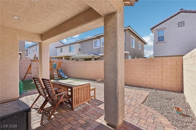 view of patio with outdoor dining area, a fenced backyard, and a playground