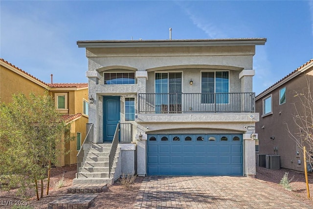 view of front of property featuring stucco siding, cooling unit, decorative driveway, and a garage