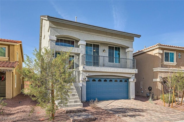 view of front of house with stairs, decorative driveway, a garage, and stucco siding