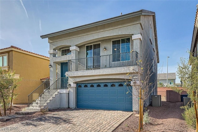 view of front of house featuring fence, an attached garage, central AC, stucco siding, and decorative driveway