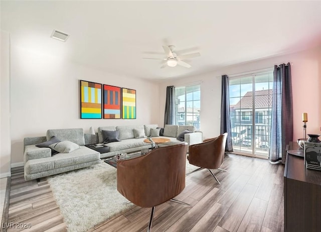 living area featuring baseboards, wood finished floors, visible vents, and ceiling fan