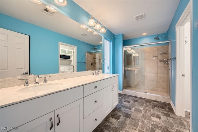 bathroom featuring visible vents, a shower stall, and a sink