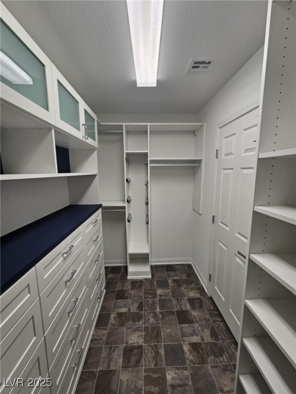 spacious closet featuring visible vents and stone finish floor