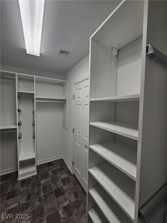 walk in closet with visible vents and stone finish floor