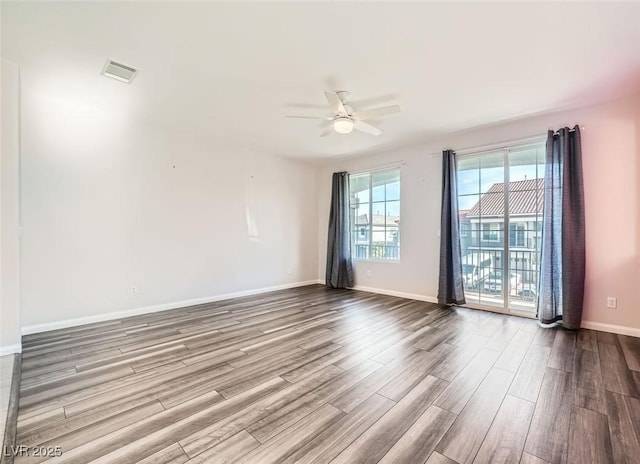 unfurnished room featuring ceiling fan, visible vents, baseboards, and wood finished floors