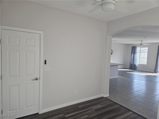 spare room with a ceiling fan, arched walkways, and baseboards