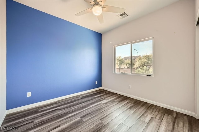 spare room featuring a ceiling fan, wood finished floors, visible vents, and baseboards