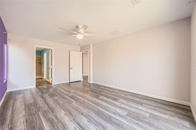 unfurnished bedroom featuring a ceiling fan, wood finished floors, baseboards, and connected bathroom