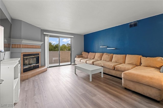 living room with visible vents, wood finished floors, and a fireplace