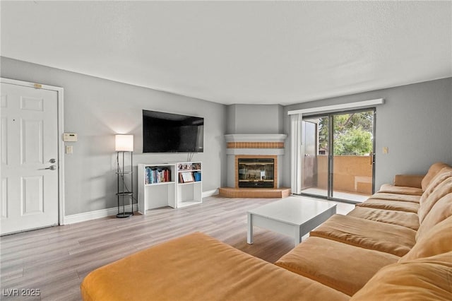 living room featuring a glass covered fireplace, baseboards, and wood finished floors