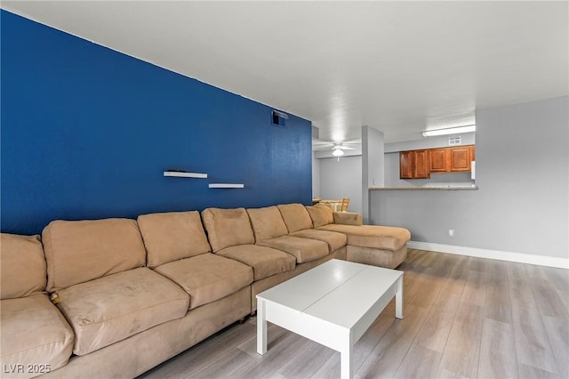 living room featuring visible vents, a ceiling fan, baseboards, and wood finished floors