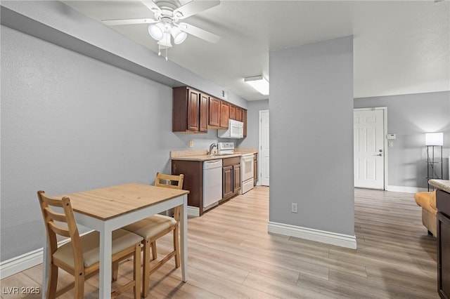 kitchen featuring white appliances, baseboards, light wood finished floors, ceiling fan, and light countertops