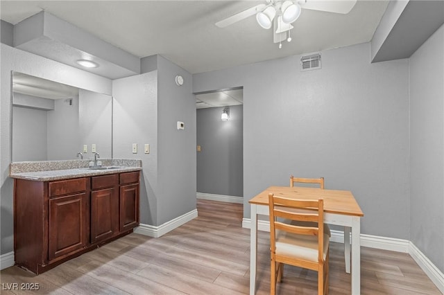 dining space with visible vents, baseboards, light wood-style floors, and a ceiling fan