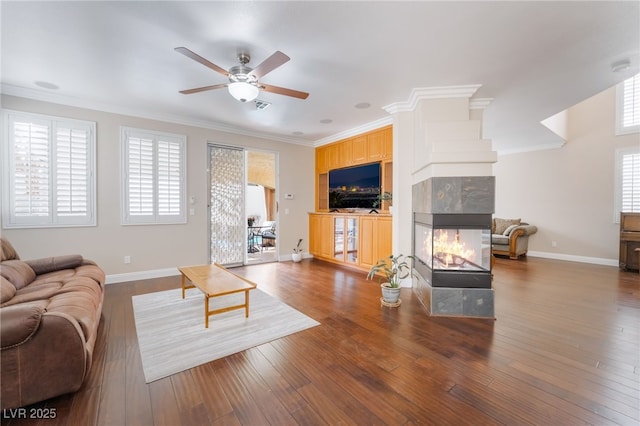 living area featuring a healthy amount of sunlight, hardwood / wood-style floors, a fireplace, and crown molding