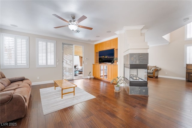 living room with a healthy amount of sunlight, hardwood / wood-style floors, crown molding, and a tile fireplace