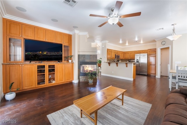 living room with dark wood finished floors, a fireplace, visible vents, and ornamental molding