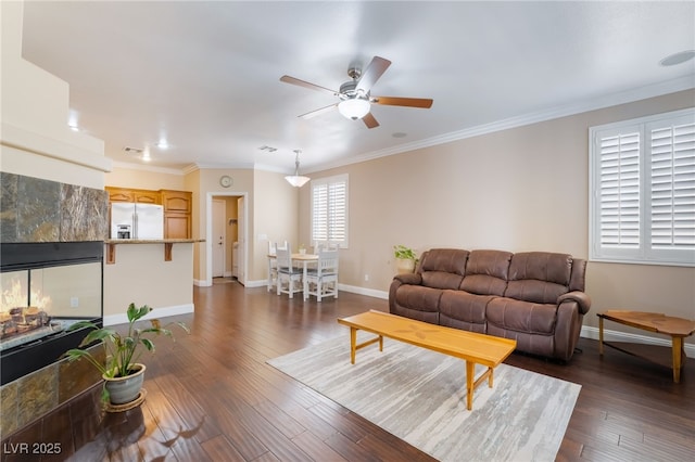 living area featuring baseboards, a ceiling fan, ornamental molding, and dark wood-style flooring