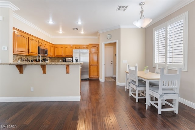 kitchen featuring a breakfast bar, visible vents, a peninsula, and stainless steel appliances