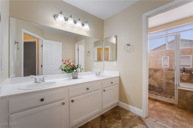 bathroom featuring a sink, baseboards, double vanity, and a shower stall