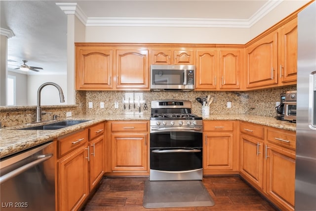 kitchen with ornamental molding, a sink, light stone counters, appliances with stainless steel finishes, and decorative backsplash