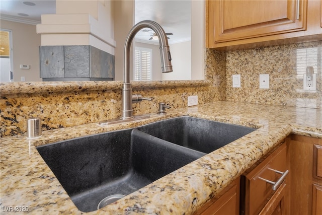 room details with decorative backsplash, crown molding, light stone counters, and a sink