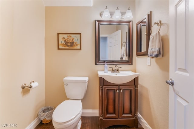 bathroom featuring toilet, vanity, baseboards, and wood finished floors