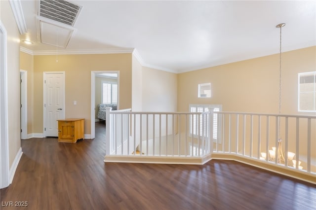 hallway featuring dark wood-style floors, visible vents, baseboards, attic access, and ornamental molding